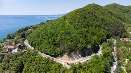 Aerial view of the highway in a picturesque area among the mountains on the seashore. Golovinka, Sochi, Russia.
