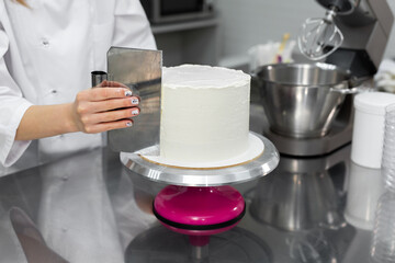 The pastry chef levels the cake with cream