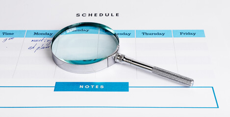 Magnifying lens glass over schedule with plans. High quality photo