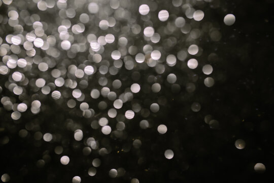 black white bokeh. Bokeh lights on a black background, shot of flying drops of water in the air, defocal drops of water levitation on a dark, blurry. Black and white blurred bokeh lights background