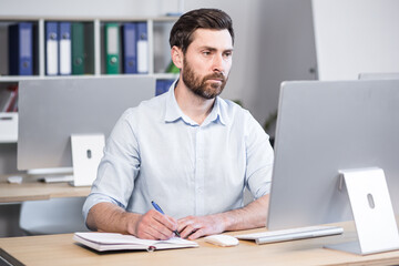 Portrait of a successful and serious businessman, pensive man looking at the camera working in the office at the computer
