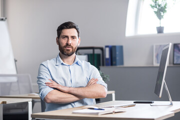 Fototapeta premium Portrait of a successful and serious businessman, pensive man looking at the camera working in the office at the computer