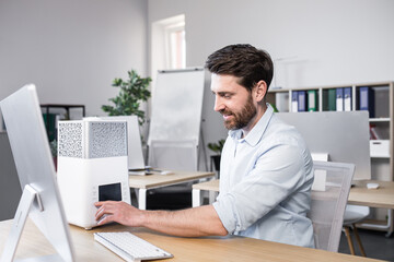Happy businessman works in office hot, turns on portable small air conditioner freshener and...