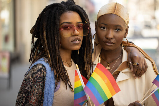 LGBTQ same sex black women couple waving rainbow flags on a city street