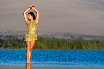 latin young woman posing on water with hands over head in dress outdoors