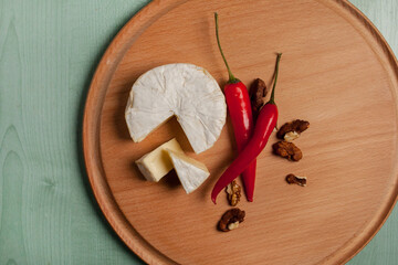 cheese brie camembert, chili and walnuts, on a wooden light background. view from above. Camembert cheese. Cheese brie camembert on a light wooden background.
Food for wine and romance. Text space.