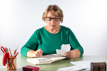 A retired woman writes down her expenses in a book. The concept of accounting for household...