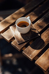 coffee in a white mug on a wooden table in the sunlight of a cozy local cafe, morning coffee