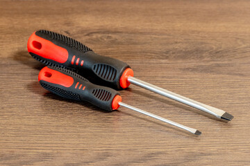 Screwdrivers of different sizes with straight tips on a wooden table