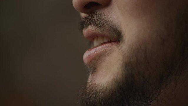 Extreme close up of an asian man's mouth talking and smiling in slow motion indoors