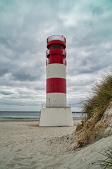 white and red lighthouse on the beach