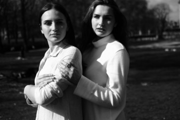 Black and white portrait of two girls. Girls in white dresses walking in the park
