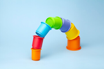 Colorful plastic cylinders composing a curved bridge, object isolated on blue background