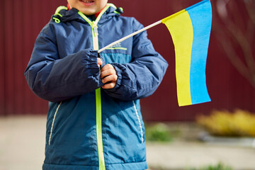 Patriotic little boy holds Ukrainian flag. Stand with Ukraine. Support Ukraine. Stop russian...
