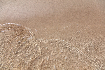 Empty sandy beach in Greece, close up top view. Sea water touch wet sand, copy space. Summer holiday