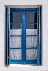 Window with blue open shutter on white wall. Cyclades island house, Greek traditional architecture.