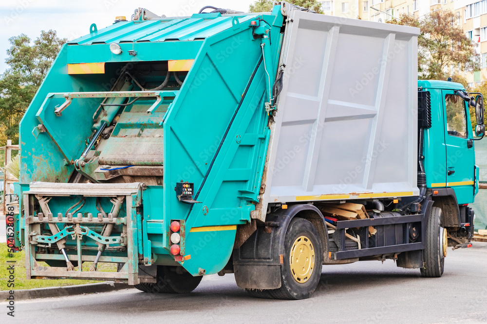 Leinwandbilder A garbage truck picks up garbage in a residential area. Loading mussar in containers into the car. Separate collection and disposal of garbage. Garbage collection vehicle.