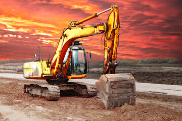 A heavy crawler excavator with a large bucket is getting ready for work against the sunset....