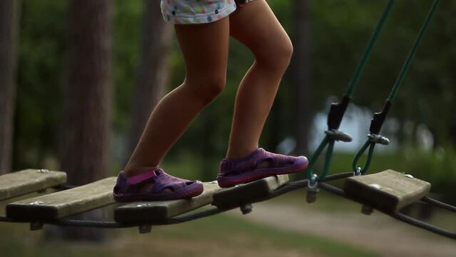  little girl walk on a rope bridge in park