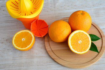 fresh oranges on cutting board and squeezer, close-up