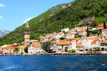 Fototapeta na wymiar Boka Kotor Bay, Montenegro. Medieval city surrounded by high beautiful mountains, church, ancient tower. View from the sea.