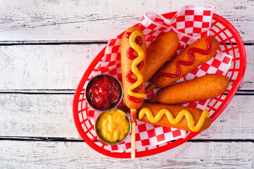 Basket of corn dogs. Above view over a white wood background. Summer fair concept.