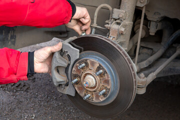 A man replaces the brake pads on a car. Security, service.
