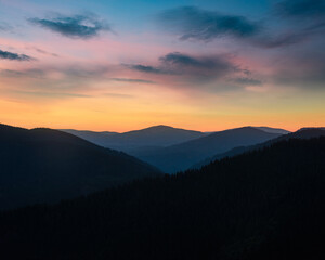 Beautiful landscape in the mountains at sunrise. View of mountains layers and colorful sky at distance in the twilight.