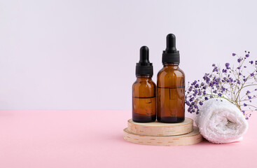 A wooden podium, a white napkin, two bottles with a pipette filled with hyaluronic acid, oil or essence. Body care concept, natural spa cosmetics