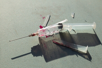 A syringe smashed to pieces with drops of blood