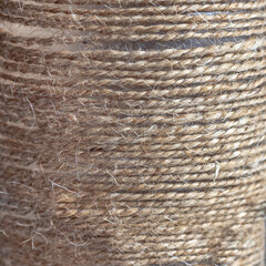 Beige linen threads are wound on a round base