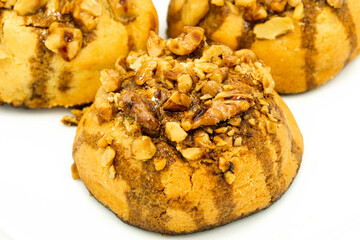 Three molasses cookies decorated with walnuts on a white background