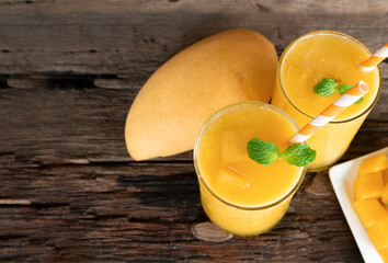 Mango smoothies orange colorful fruit juice beverage healthy high protein the taste yummy in glass on wood background from top view.
