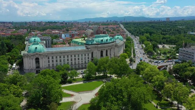 4K Aerial view of capital of Bulgaria, Sofia. Iconic building of the world-famous Sofia University Saint Kliment Ohridski. Roofs of buildings, streets and park in Sofia.