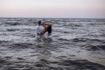 couple in love hugging in the sea at sunset