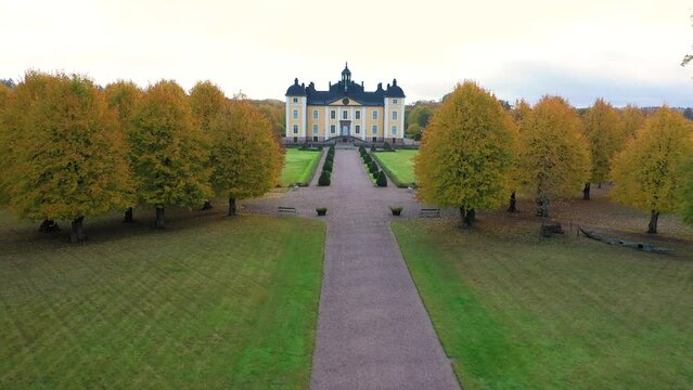 Castle or royal palace by lake or water with a beautiful autumn park. Beautiful building aerial drone shot from above in Sweden.