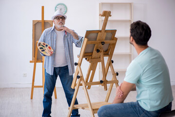 Old painter and young male model at the studio