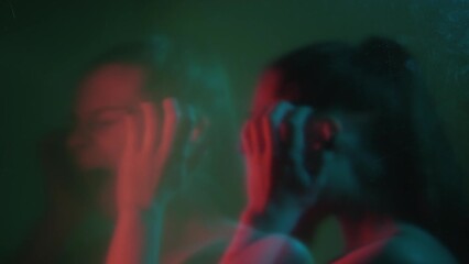 Bipolar disorder. Mental stress. People emotion. Manic syndrome. Defocused double exposure depressed worried woman screaming on dark out of focus background.