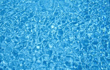 Blue water of a swimming pool. Sun reflection and ripple on blue water. Background of swimming pool water.