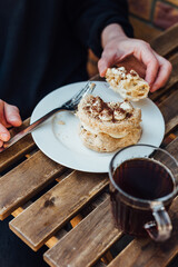 meringue cake on a plate hands take a piece, eat sweets in a cafe
