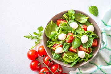 Green salad with fresh leaves, tomatoes and mozzarella. Top view, copy space.