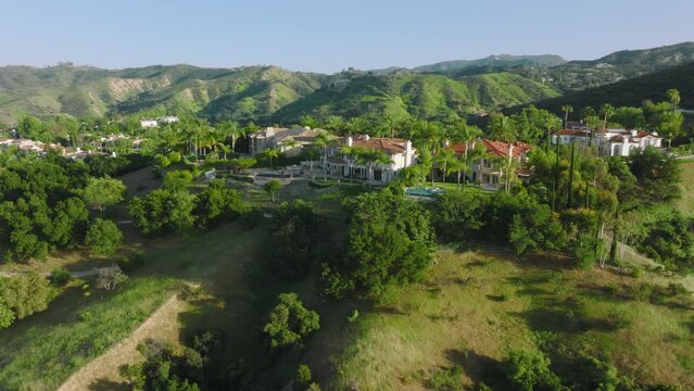 Beautiful mansion in Calabasas Park for the perfect retreat as seen from above. Aerial view of the residence hiding in lush greenery of the hilly landscape with sunny skyline. High quality 4k footage
