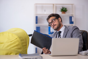 Young male employee looking after new born at workplace
