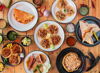 Mesa servida con tacos y varios platillos de comida mexicana, molcajete con carne al pastor al...