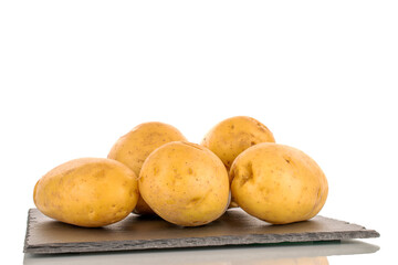 Several raw organic potatoes on a slate stone, close-up, isolated on a white background.