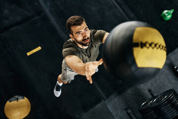 Above view of sportsman throwing medicine ball while working out at gym.