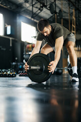 Male athlete preparing barbell for weightlifting training in gym.