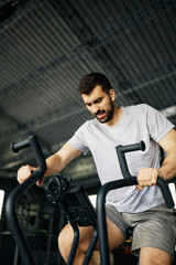 Fototapeta na wymiar Determined athlete spinning on exercise bike during cross training in gym.