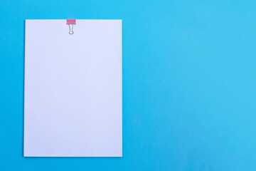 white paper with clip on blue background.