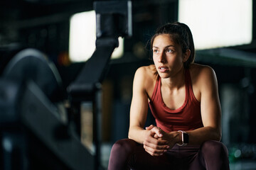 Young athletic woman takes break while working out in  gym.